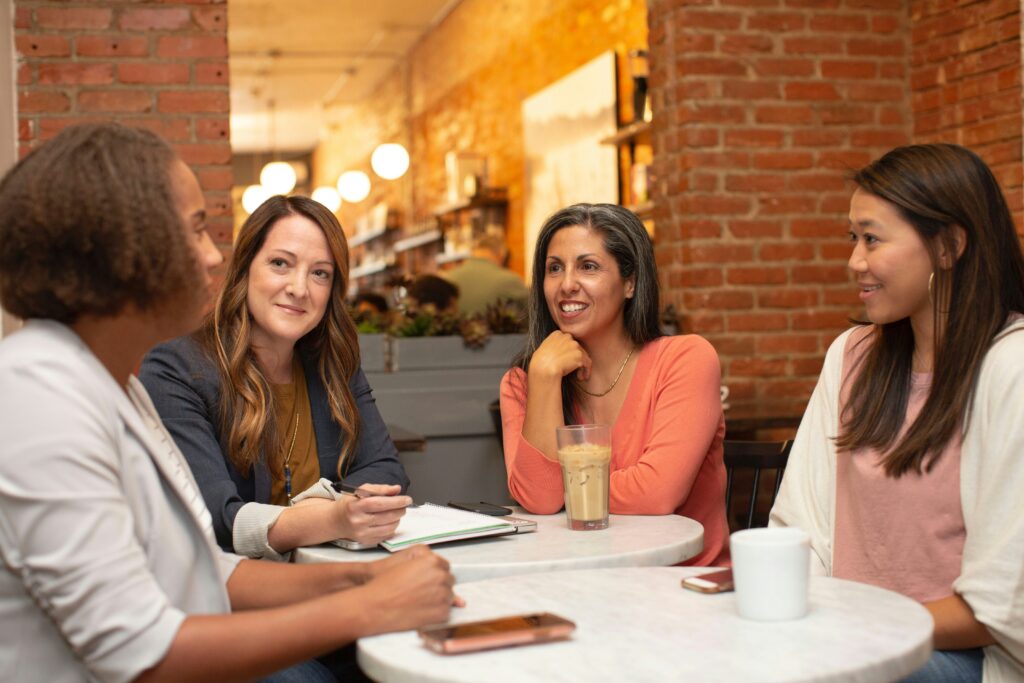 Women sitting at a café table, talking about direct marketing strategies