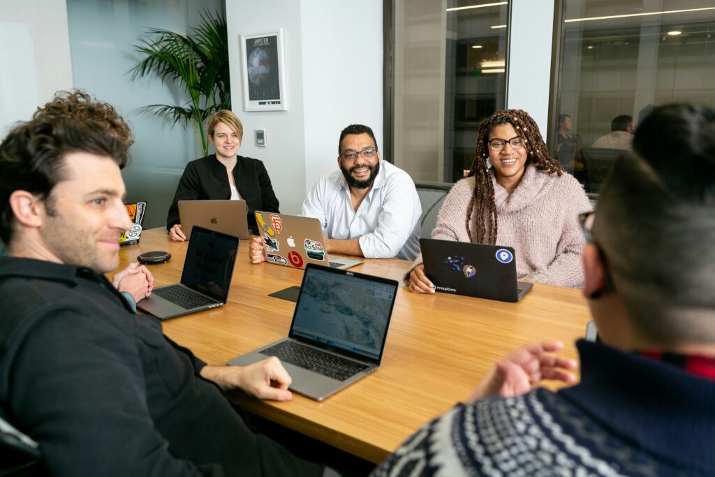 Team members gathered around a conference table with open laptops during a meeting